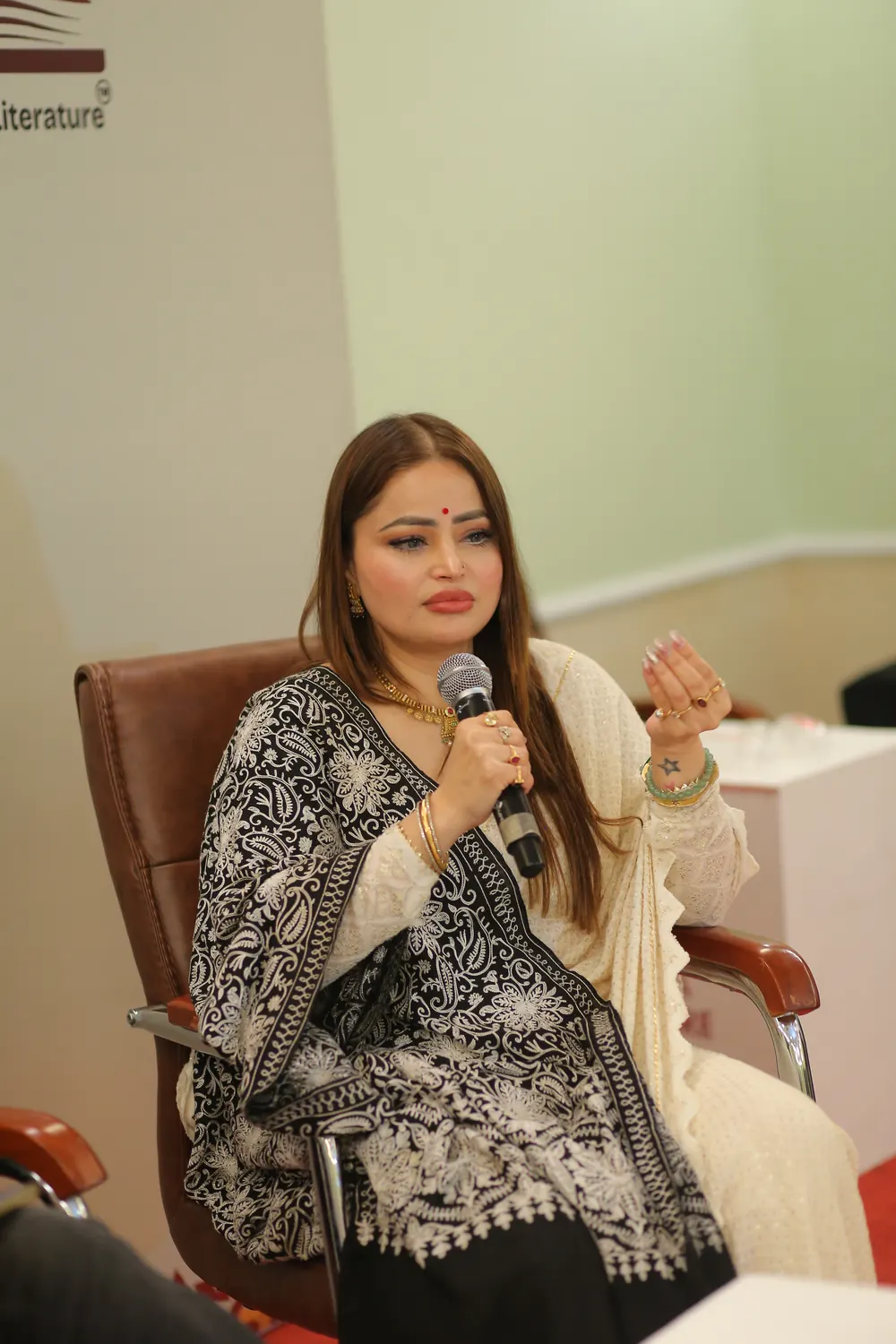 Ms. D. Aaliya in a black chikankari kurta speaking on a panel at the Nalanda Literature Festival